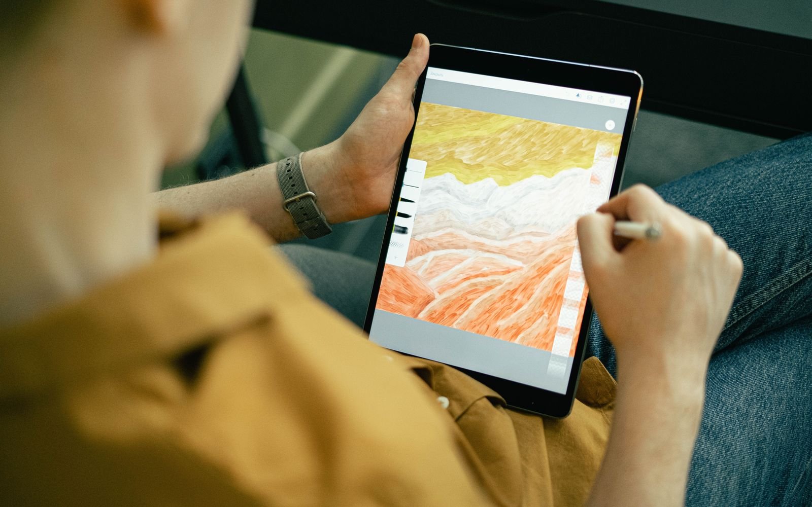 A person sketching colorful digital art on a tablet with a stylus